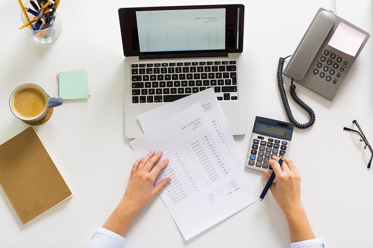 hands of a woman with calculator, papers and laptop computer